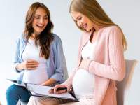 pregnant woman sitting next to each other smiling